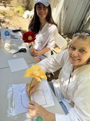 Friends enjoy a paper flower workshop in the Swirl courtyard at Allied Arts.