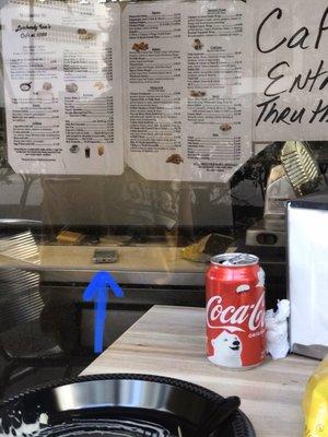 Cell phone sitting on the cutting board where they prepare food / sandwiches