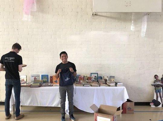 Local high school students browsing donated books to read and enjoying their drawstring backpacks from SchoolsFirst Federal Credit Union.