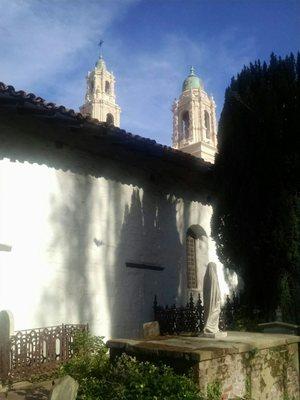 View of Basilica steeples from old mission cemetery; some markers dating to 1802.