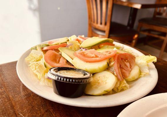 Side view of the House Salad; onions, cucumber, avocado on lettuce