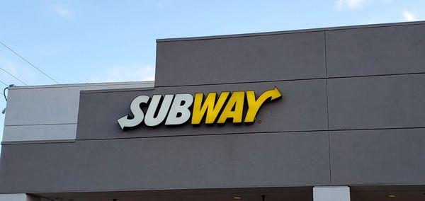 Subway sign on the top of the storefront.