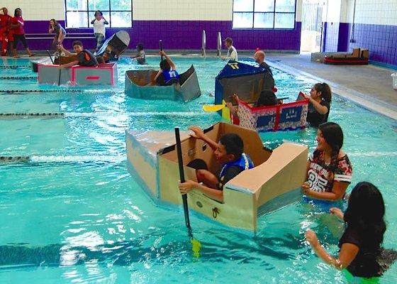 Students race the boats they designed and built from cardboard as part of an interdisciplinary project.