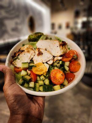 A seasonal bowl with grilled chicken, bibb lettuce, and tomato/cucumber mix.