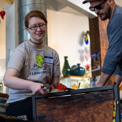 A photo of a glassblowing class student creating a paperweight.