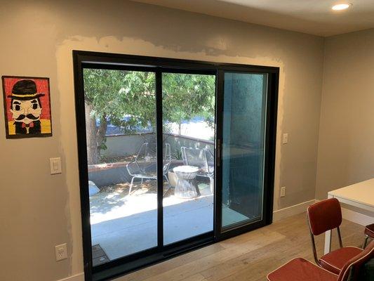 International Windows Multi-slide door with screens and flush handles installed retro-fit with aluminum trim coil wraps.