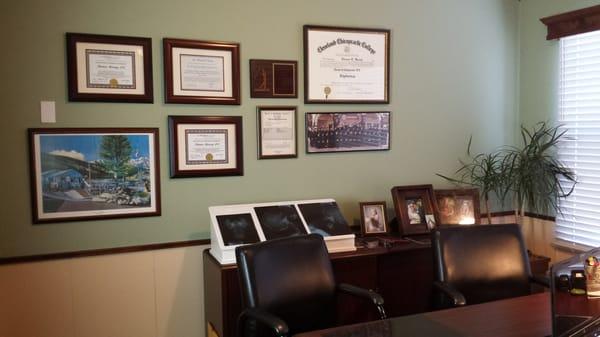 Seats for consultations in Dr. Harvey's office, with his credentials and lovely family photos in the back