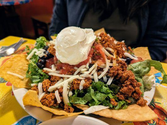 Tostada. $8.25. Black beans, crispy corn tortilla, lettuce, cheese, tomato, salsa fresca, sour cream, chips, chorizo (spicy pork sausage).