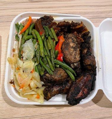 Loaded medium combo plate of Stewed Oxtail, Jerk Wings, vegetables, and rice and beans underneath