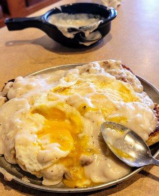 Southern tradition: Two giant grilled biscuits fresh pipin hot, sausage gravy two eggs over medium on top