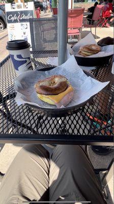 Cafe latte and breakfast bagel with egg, ham, and cheese