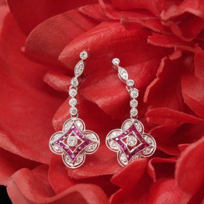 These Art Deco style quatrefoil earrings have a beautiful mix of French cut rubies and round brilliant diamonds and hang 1.23 inches.