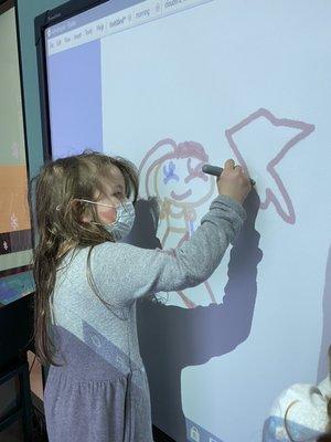 Kindergarten after school play. Student drawing on the interactive whiteboard