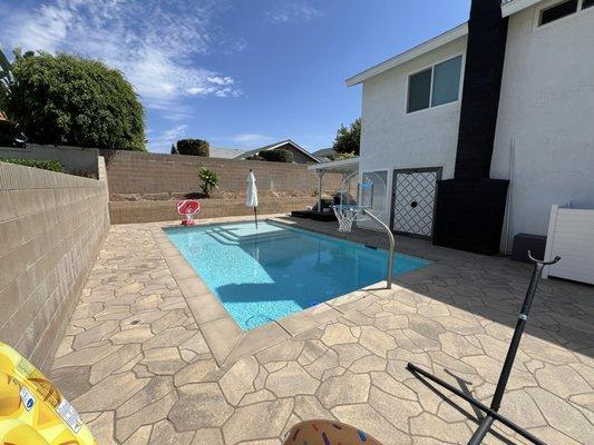 Backyard pool with baja shelf, removable hoop, and outdoor shower.