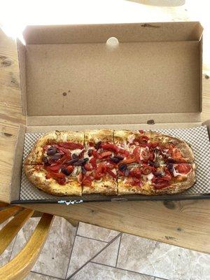 Pizza with vegan cheese, tomatos, roasted peppers, olives and roasted garlic sauce