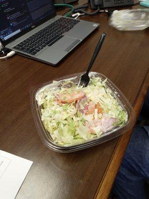 An upside down salad, pre-dressed w/ large slices of tomato, one banana pepper ring, w/ only ham in a "Italian BMT" salad.