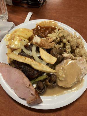 Ham, steak, turkey with gravy, stuffing, baked beans, fries, mushrooms, veggies, and cheesy potatoes