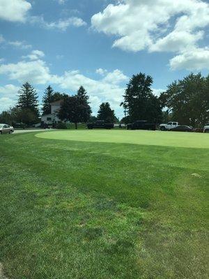 Putting green and clubhouse in background.