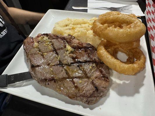 12oz ribeye steak with mashed potatoes and onion rings.