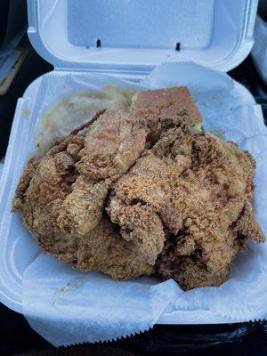 Fried chicken, mashed potatoes and gravy and greens under the paper