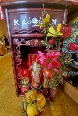 Altar with fresh flowers, fruit, and candles.