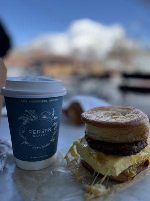 Breakfast sandwich with sausage and a cup of latte