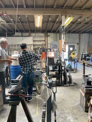 Charlie helping a student forge his knife.