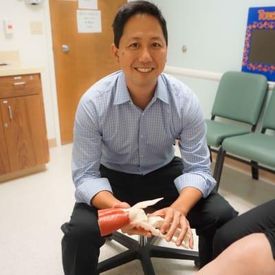 Dr. Huh explaining how a knee injury occurs to a patient.