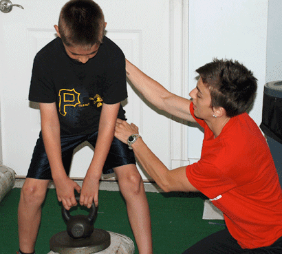 Coach Kelsey providing feedback and positional cues to a young athlete.