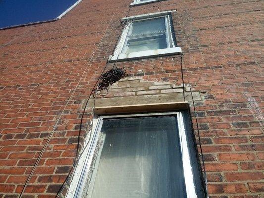 Replaced falling brick and a header on the side of a house above a window