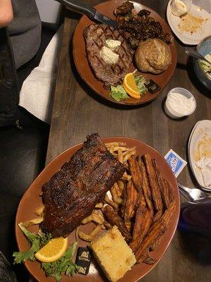 Ribeye steak with Brussel sprouts and baked potato. Half rack of ribs with fries, Sweet potato fries, and corn bread.