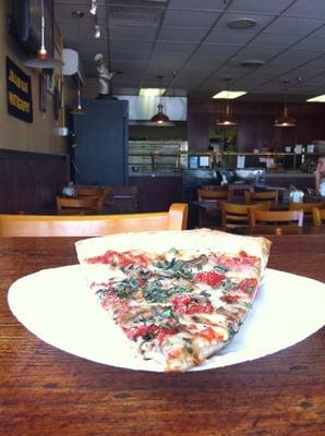 Just a delicious slice of pizza with tons of fresh basil in their newly redecorated restaurant.