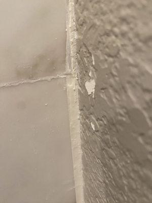 Wide caulk stip from uneven porcelain trimming.