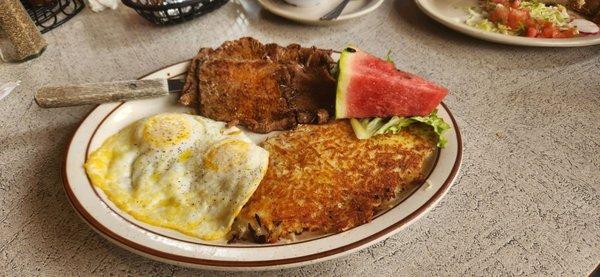 Steak and eggs, hash brown potatoes, and spicy salsa