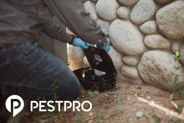 A Pest Pro technician setting up an exterior rodent bait station.