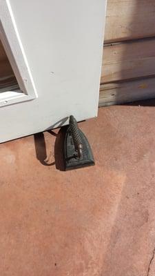 Old iron being used as a doorstop.