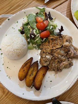 Seasoned shredded pork with plantains and rice and salad.