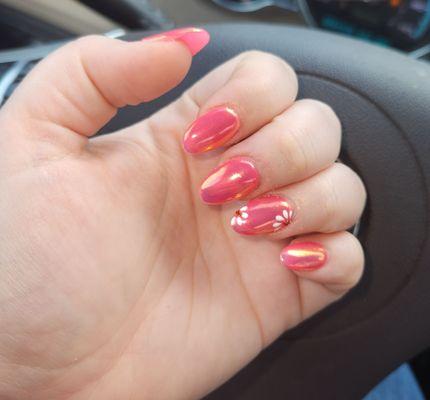 Beautiful pink nails with a chrome shimmer on top and flower design on ring finger