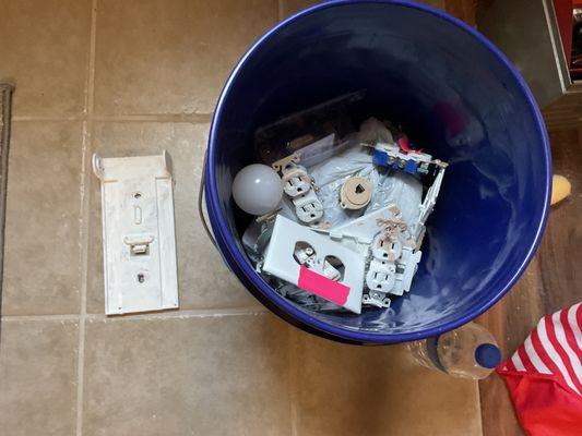 Bucket of face plates and electrical plugs that were painted on