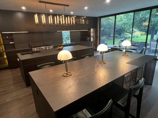 Kitchen with 2 island in Dekton Laurent material. Waterfall panels with mitered edge. Notice the metal steel detail in the island.