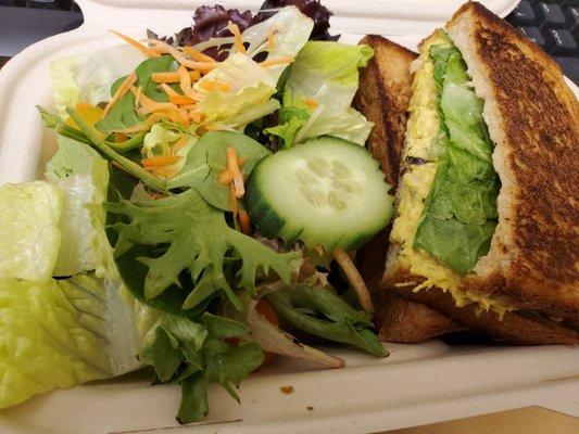 Curried chicken sandwich and salad in a compostable container.