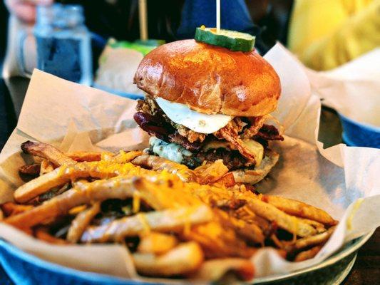 Boar burger with fried egg, bacon, and fried onions along with cheesy, gravy fries.