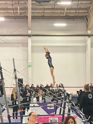 My child competing for Gold Star Level 3 Team dismounting the uneven bars.