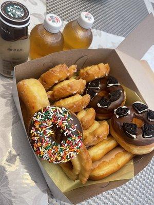 Some delicious donuts, Oreo cookie, old fashioned, sprinkles, maple and chocolate bars. Apple juice and coffee.