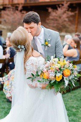 Bride and Groom kissing featuring a yellow bouquet.