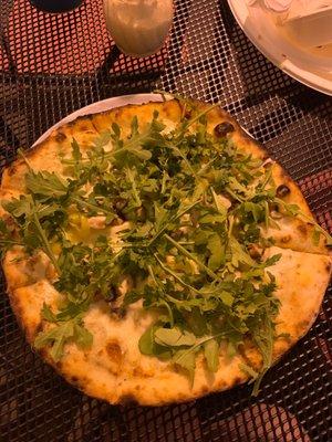 Pizza with white sauce, banana peppers and arugula