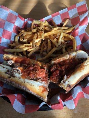 Small cheesesteak with a drizzle of marinara and fries