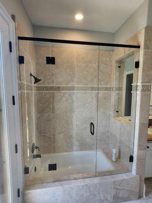 Custom frameless shower door with a stationary panel inside the window opening.