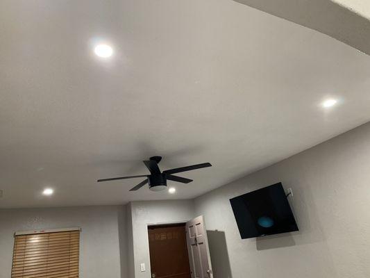 4 recessed lights and a ceiling fan and a "floating" tv.