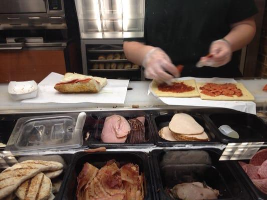 A spicy Italian and a couple of Flatizzas (pizza) being made